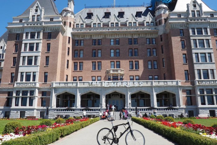 Bicycle in front of a large historic building with 'Empress' sign, surrounded by gardens.